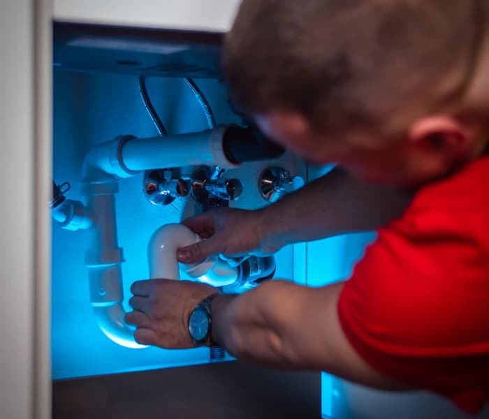 Plumber fixing pipes under a sink